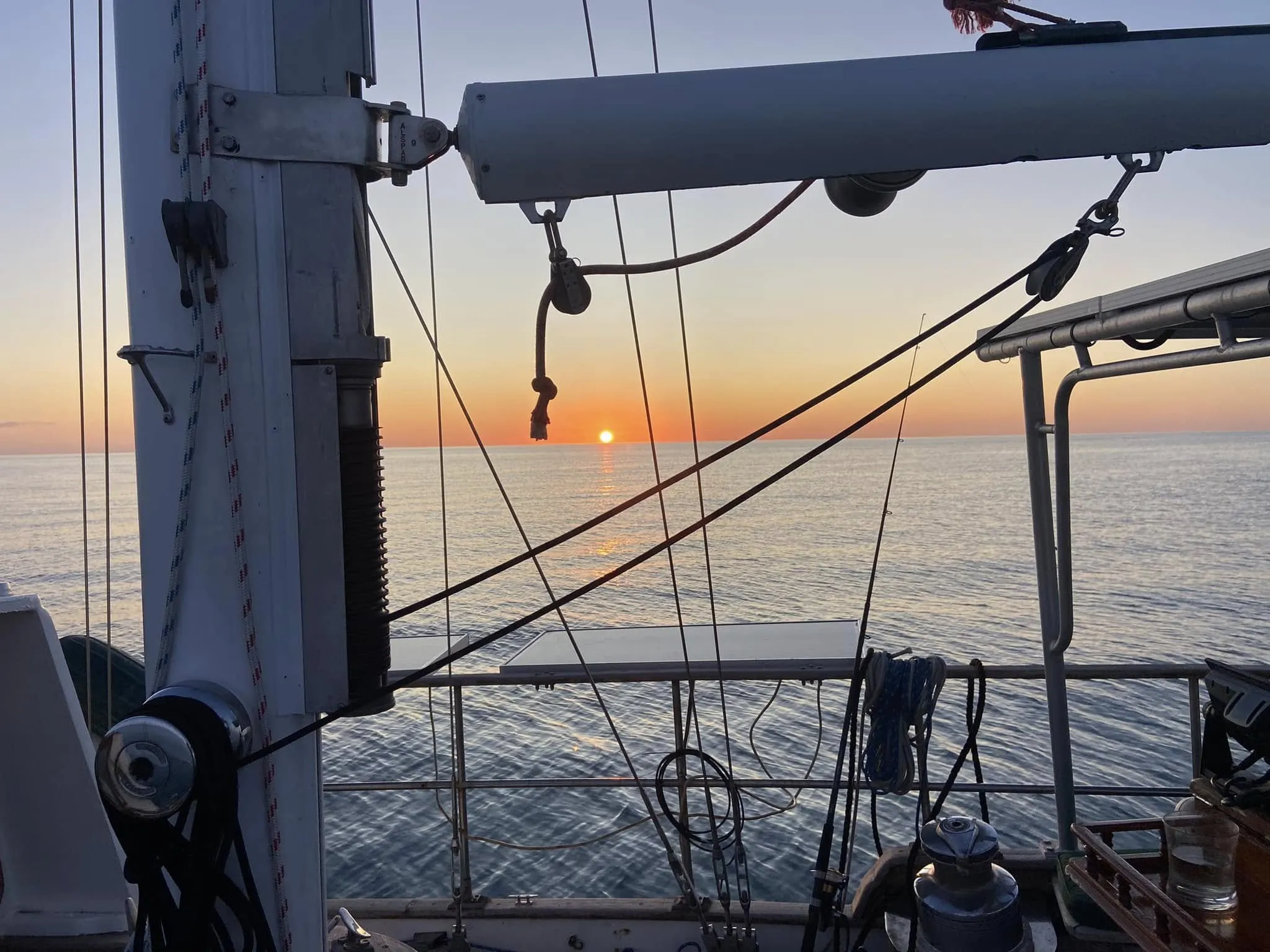 Sunset over calm water seen through Sea Dragon's rigging