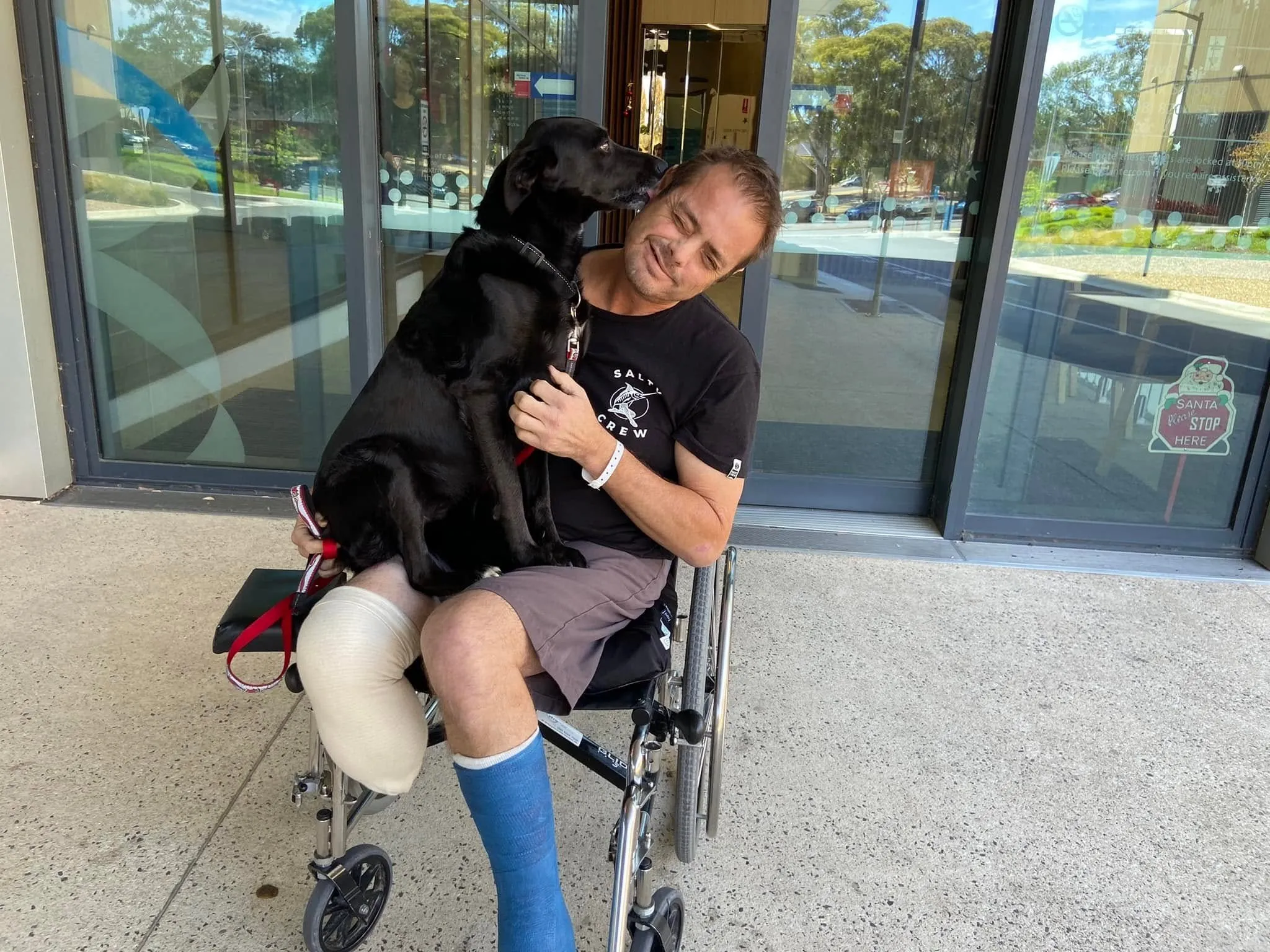 Tim in a wheelchair just out of hospital, hugging his dog Maisey